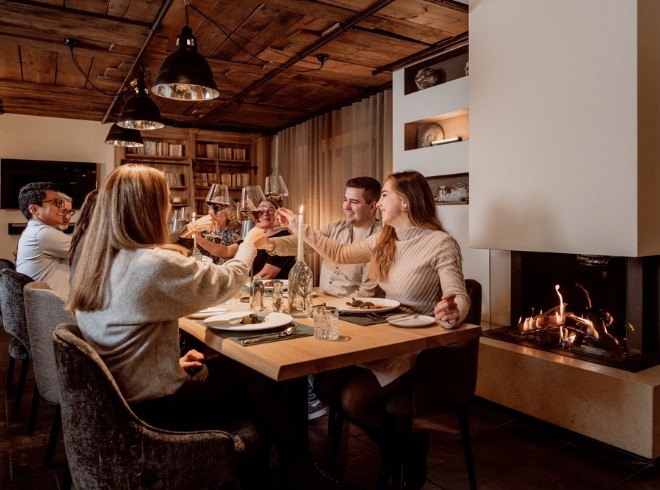 Freunde sitzen im KräuterSchmied und stoßen mit einem Glas Wein an