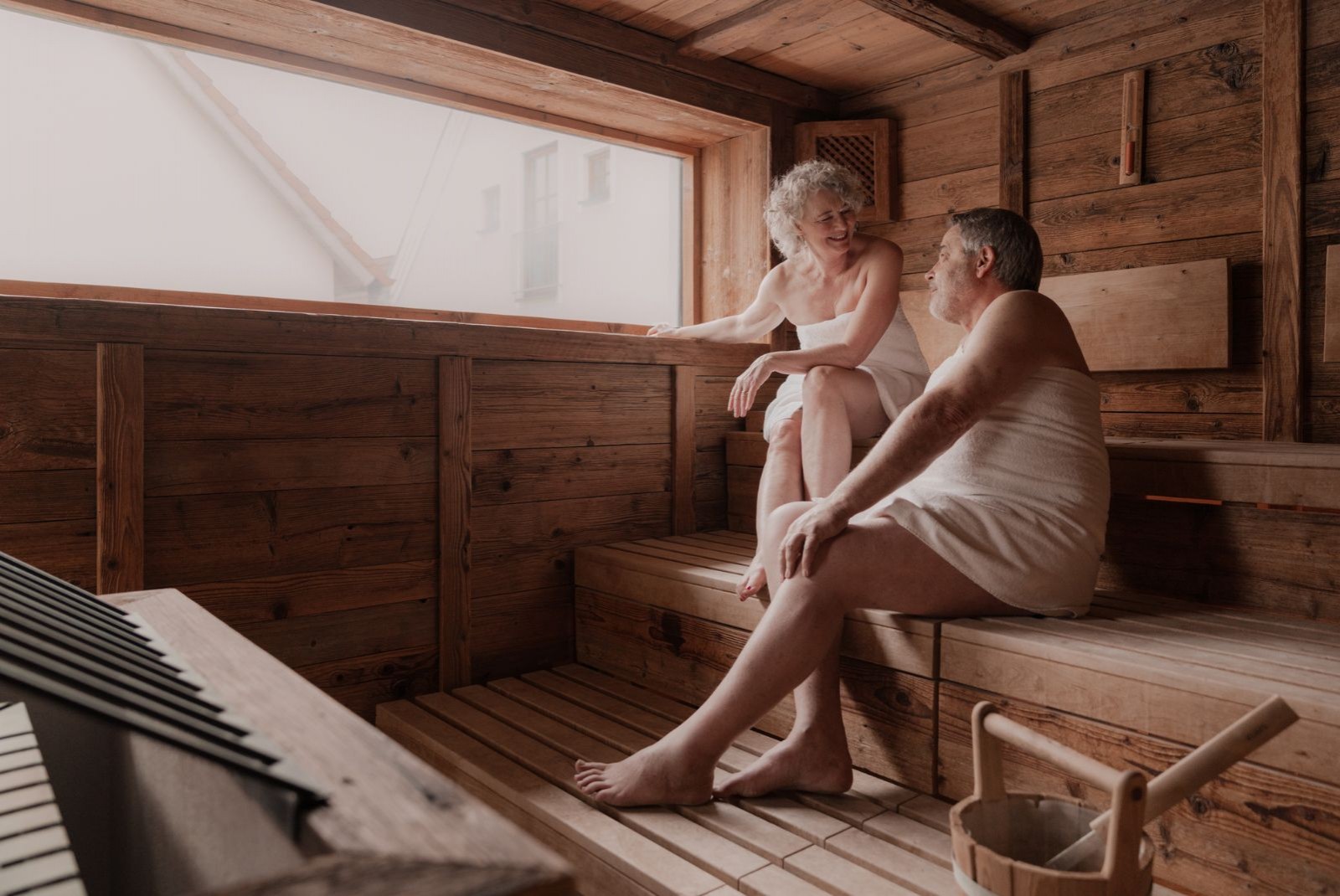 Ein Pärchen entspannt zusammen in einer Sauna, umgeben von Holzverkleidungen